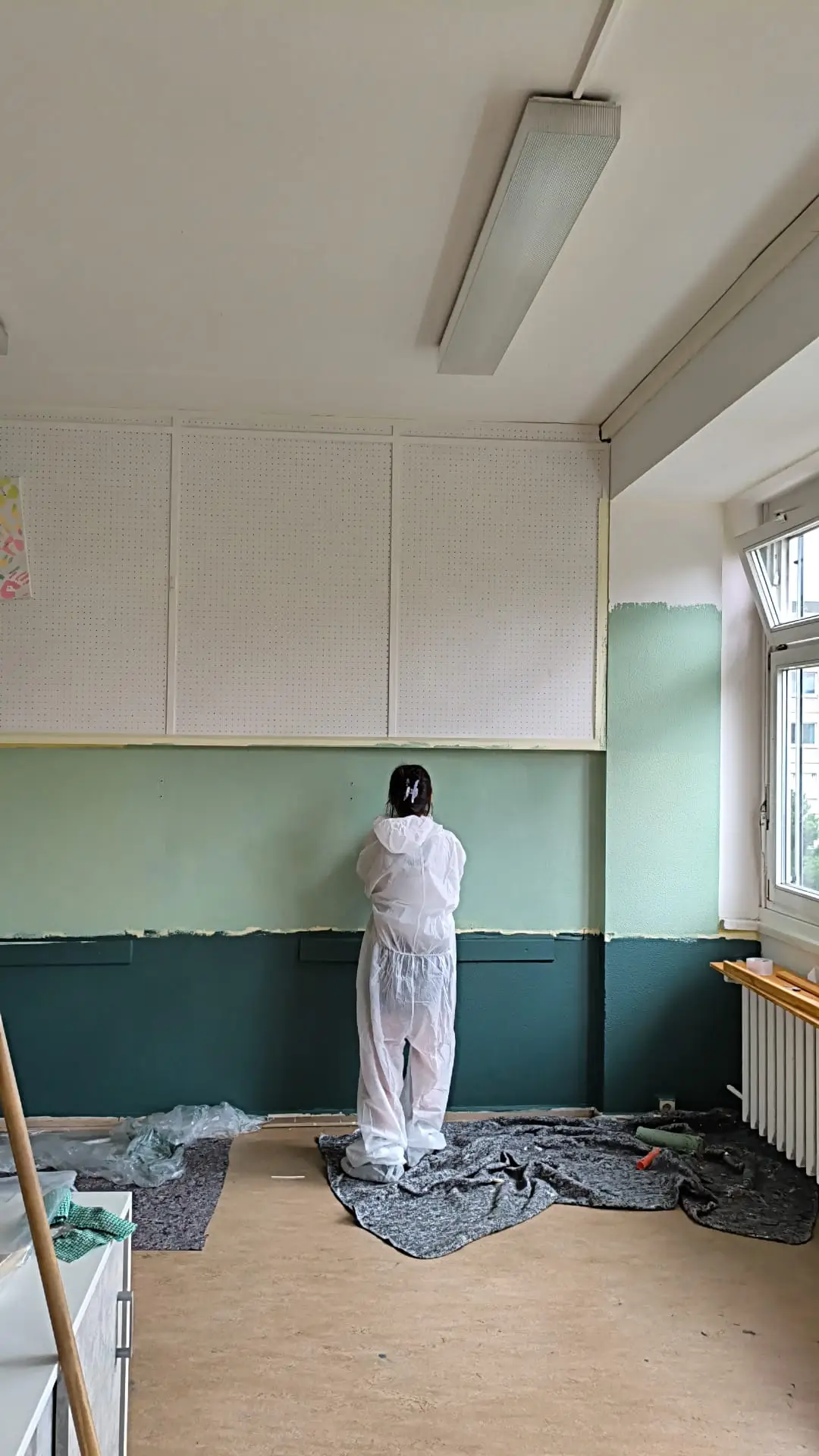 Ein Schüler streicht sorgfältig eine Wand im Klassenraum