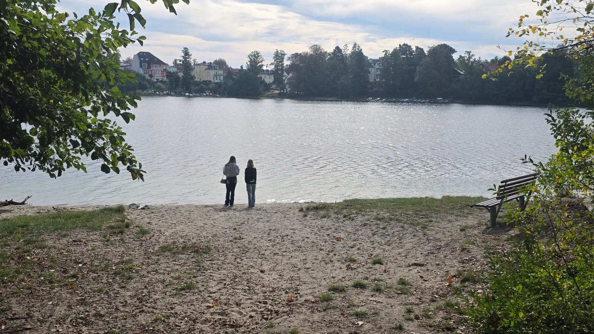 Zwei Schülerinnen stehen am Ufer des Straussees und blicken auf die Häuser am gegenüberliegenden Ufer.